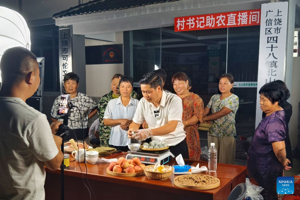 Chen Jianguo (C, front), Party secretary of Beishan Village, promotes agricultural products at a livestream session in Beishan Village of Guangxin District in Shangrao City, east China's Jiangxi Province, July 10, 2025.
Chen Jianguo, Party secretary of Beishan Village, opened social media accounts to post farm produce promotion clips and leveraged livestreaming to sell local agricultural products. Villagers pack their produce up to his livestream sessions one after another, creating a bustling scene similar to open-air markets.
As e-commerce is increasingly employed to boost farmers' incomes, Party members and village officials are mobilized to participate actively in livestreaming sales, leading the way in navigating this new path to prosperity. (Photo by Zheng Hanlin/Xinhua)