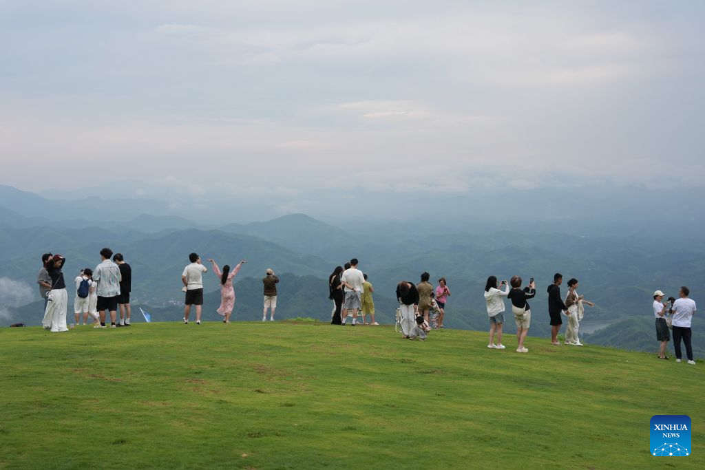 Visitors take pictures on the top of a mountain in Anji County, east China's Zhejiang Province, Aug. 5, 2026. During the summer vacation, Anji County leverages its cool weather and beautiful scenery, attracting numerous tourists to escape the summer heat. (Xinhua/Huang Zongzhi)