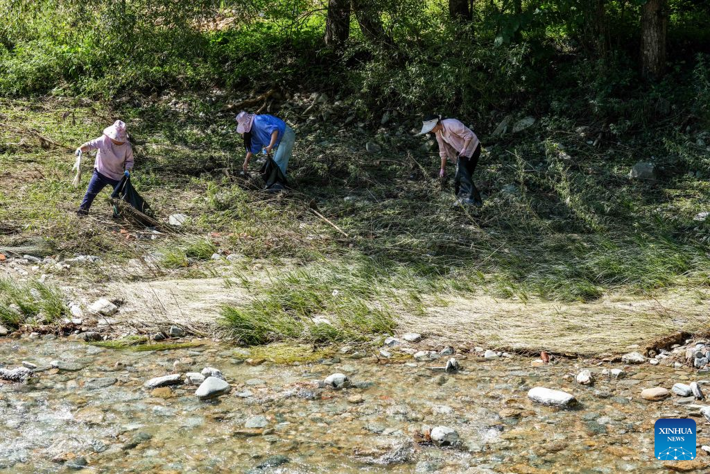 Villagers remove garbage and debris from the riverbank at Zhangjiahe Village of Kangxian County in Longnan City, northwest China's Gansu Province, Aug. 4, 2026. Kangxian, which suffered from heavy rainfall recently, has initiated campaigns to clear up rivers and restore drinking water facilities in the county, striving to bring people's work and daily life back to normal. (Xinhua/Lang Bingbing)