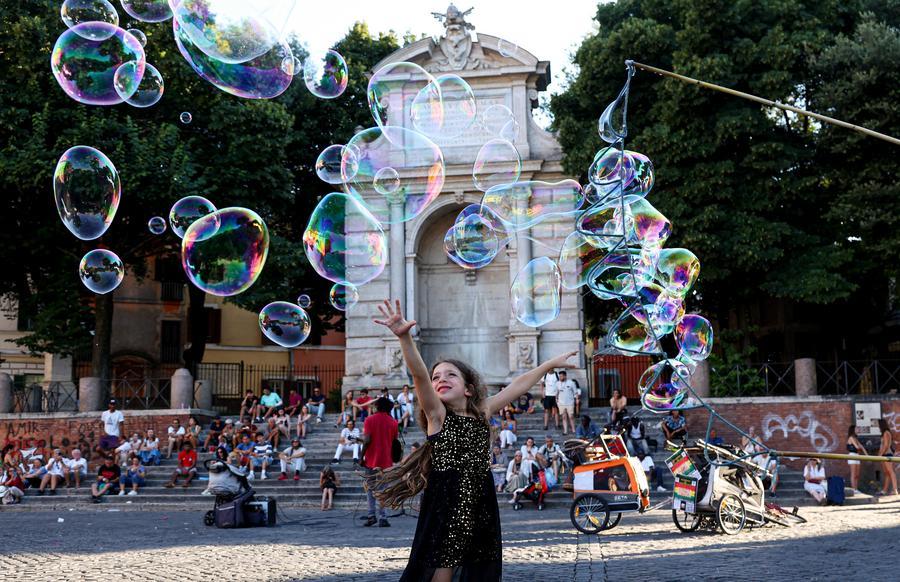 A girl plays with bubbles on a square along the Tiber River in Rome, Italy, July 12, 2026.  (Xinhua/Wang Kaiyan)