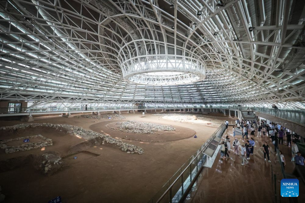 People visit an exhibition hall within the Niuheliang national archaeological relic site park in Chaoyang City, northeast China's Liaoning Province, Aug. 4, 2026. The Niuheliang national archaeological relic site park was built on the Niuheliang site, a large-scale prehistoric ritual and burial complex featuring the temple of the goddess, altars and stone tombs. Dating back more than 5,000 years, the site unearthed stone tools, pottery and jade artifacts with dragon, phoenix and human motifs, reflecting the rituals and beliefs of the Hongshan culture. (Xinhua/Pan Yulong)