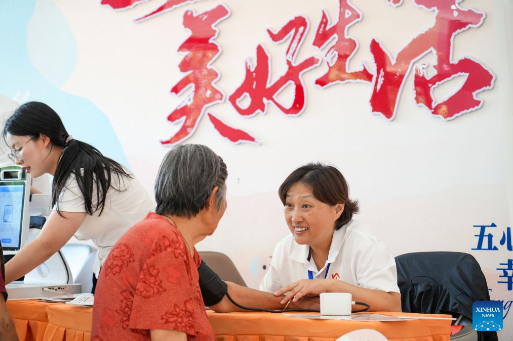 A staff member of domestic services measures blood pressure for a senior citizen in Heze City, east China's Shandong Province, July 20, 2026. A number of domestic services brands have emerged in Shandong in recent years, offering widely ranging services such as eldercare, maternity care, and in-home caregiving. (Photo by Li Baozhu/Xinhua)