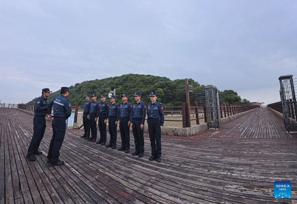 Law enforcers from China Coast Guard stand in formation ahead of an island patrol mission on the Dajinshan island in Shanghai, east China, Sept. 18, 2026. Dajinshan island boasts an excellent natural environment. To better secure the biodiversity and the ecology on the island, members of the local coast guard regularly patrol here to check the growth of native vegetation, watch out for possible invasion of alien species, and monitor the water quality in the surrounding sea area. (Xinhua/Fang Zhe)