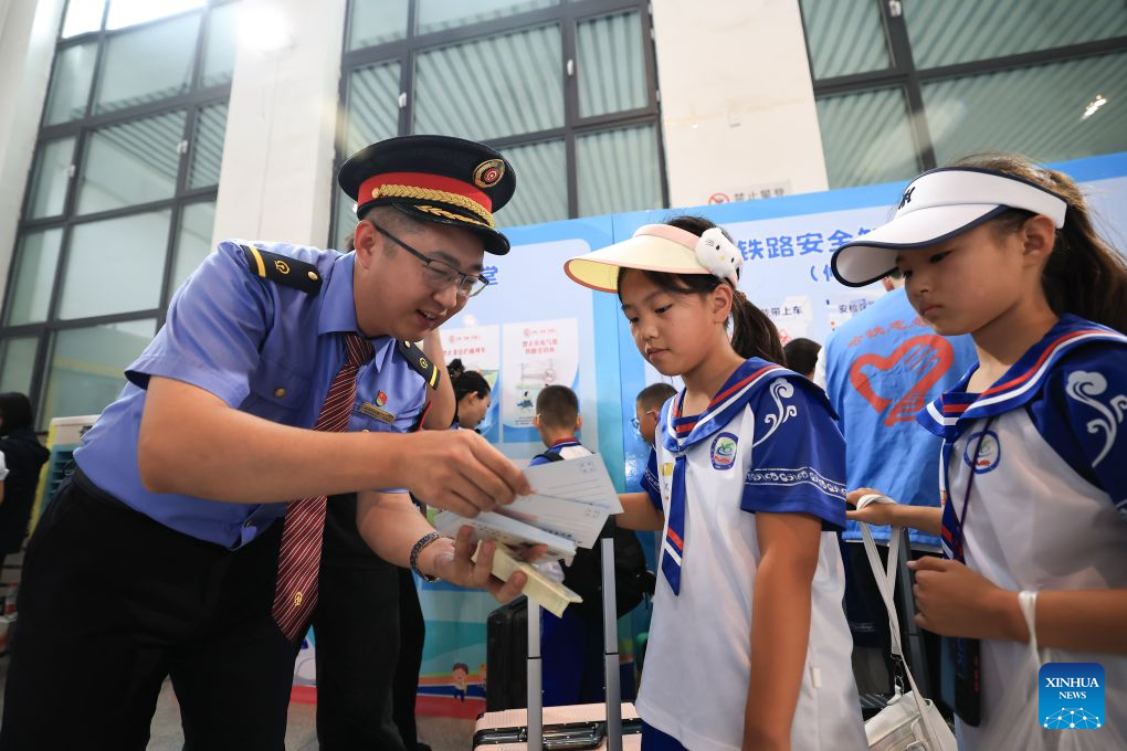 A staff member gives out postcards to students waiting to board a special train for study tour at Qiqihar railway station in Qiqihar, northeast China's Heilongjiang Province, on Aug. 9, 2026. The Y404 special train for a study tour carrying 598 teachers and students on Sunday departed from the Qiqihar railway station in northeast China's Heilongjiang Province to Beijing, capital of China.

The Heilongjiang-to-Beijing train is specially organized by China Railway Harbin Bureau Group Co., Ltd. this year for students on study tours, serving as a mobile classroom with singing and dancing activities held on it, where students on their way have the chance to interact and experience the charm of cultures. (Photo by Xu Shuai/Xinhua)