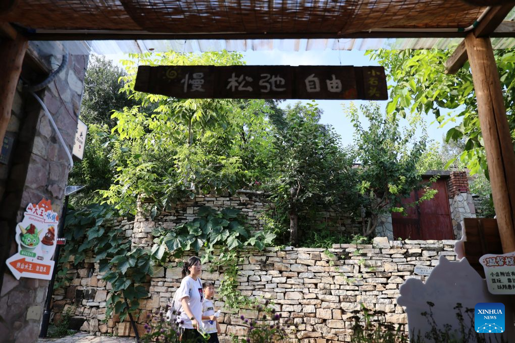 A visitor walks with her child in Xijingyu Village, Jizhou District of north China's Tianjin Municipality, Aug. 4, 2026. During summer vacation, Xijingyu Village has attracted lots of visitors. Known as the Stone Village, it is famous for its distinctive houses and alleys built of stones. (Xinhua/Li Ran)