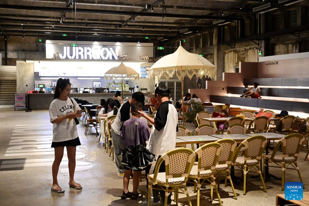 People enjoy themselves inside an art space, which is transformed from an idle warehouse, at the Chongwu ancient ferry terminal scenic area in Hui'an County of Quanzhou, southeast China's Fujian Province, Aug. 17, 2026. The Chongwu ancient ferry terminal covers an area of 33 mu (about 2.2 hectares) in Hui'an County of southeast China's Fujian Province. In 2024, local authorities transformed it from an idle terminal into a coastal vacation destination that integrates art galleries, a pier runway, trendy restaurants, and family playgrounds. (Xinhua/Lin Shanchuan)