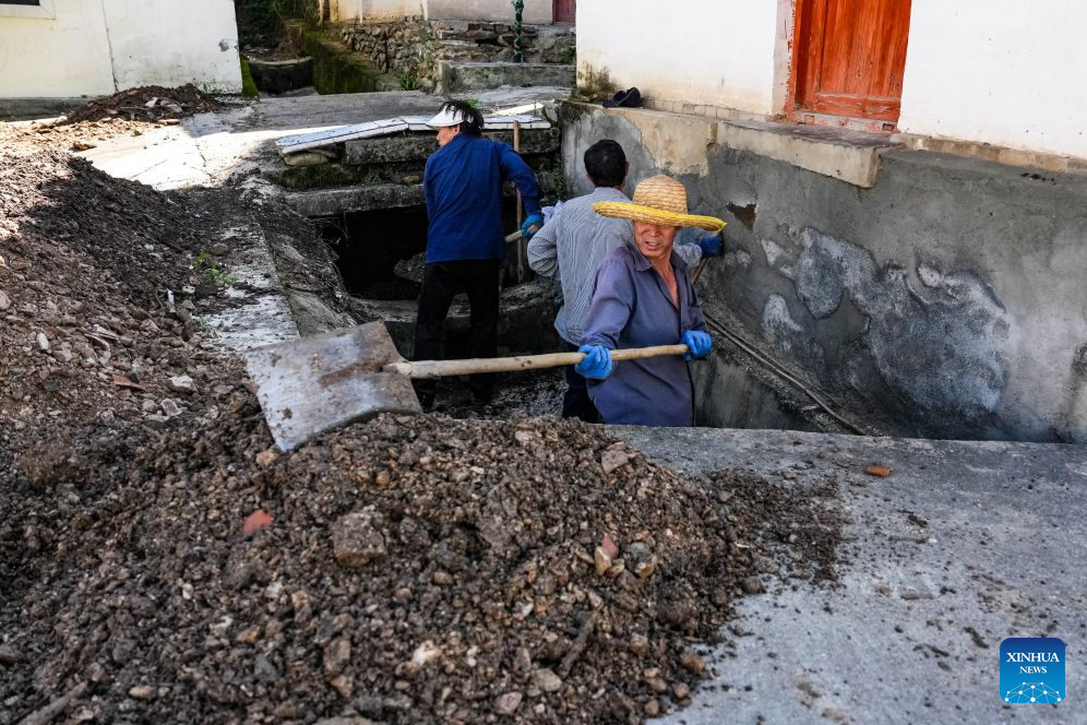 Villagers remove mud and gravel from a drainage ditch at Jiedao Village of Kangxian County in Longnan City, northwest China's Gansu Province, Aug. 4, 2026. Kangxian, which suffered from heavy rainfall recently, has initiated campaigns to clear up rivers and restore drinking water facilities in the county, striving to bring people's work and daily life back to normal. (Xinhua/Lang Bingbing)