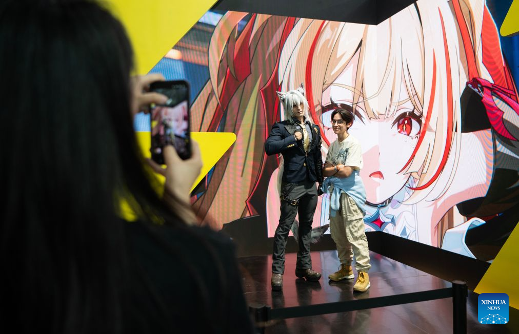 A visitor (R) poses for photos at the booth of HoYoverse at Gamescom 2026 in Cologne, Germany, Aug. 26, 2026. The world's largest trade fair for computer and video games Gamescom kicked off here on Wednesday. The five-day event is attended by more than 1,600 exhibitors from 67 countries and regions, over 70 percent of whom are international companies. (Xinhua/Zhang Haofu)