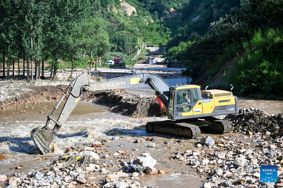 A staff member operates an excavator to clear a river channel in Baimutang Village, Kuancheng Manchu Autonomous County of Chengde, north China's Hebei Province, July 13, 2026. Recently, heavy rainfall lashed four townships and nine villages in Kuancheng Manchu Autonomous County. Local authorities have launched relief efforts to restore infrastructure and normal life. (Photo by Wang Liqun/Xinhua)