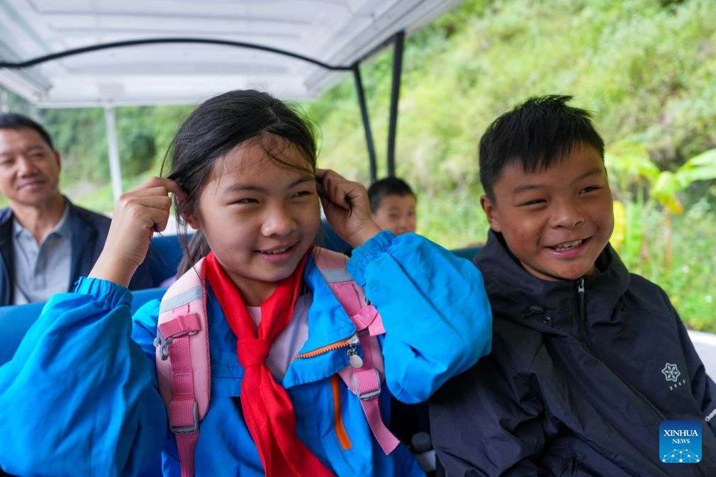 Students take a shuttle vehicle on their way to school in Puli Township, Xuanwei City, southwest China's Yunnan Province, Aug. 30, 2026. Nizhuhe Village is located at the bottom of the Nizhu River Grand Canyon in southwest China's Yunnan Province. What separates Nizhuhe Village and the Guanzhai primary school on the mountain top is a vertical drop of over 500 meters. Students living at the canyon bottom used to take nearly half a day to travel from home to school.
In 2022, significant changes in the means of local commuting took place upon the completion and opening of the Nizhu River Grand Canyon scenic area, which came with a 268-meter-high cliff elevator and a cable car system that were available to local villagers, including students, free of charge.
Today, the combination of sightseeing shuttle vehicles, elevators and cable cars has shortened students' journey to school to about 30 minutes. A dedicated passage has also been set up for them, with police officers and dedicated staff members deployed along the commuting route. (Xinhua/Chen Xinbo)