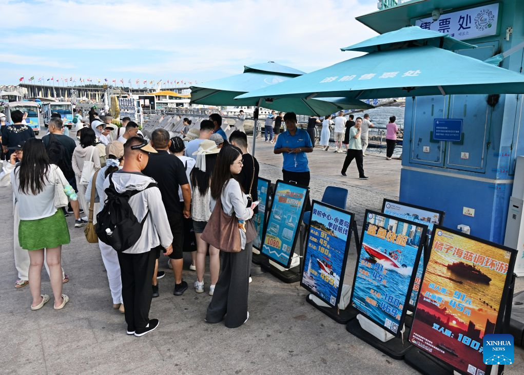 Tourists check the information about sightseeing boats in Qingdao, east China's Shandong Province, Aug. 26, 2026. The Qingdao Olympic Sailing and Marine Culture Tourism Area has been promoting sea sightseeing by launching a number of sightseeing routes linking destinations from Jiaozhou Bay to Zhaitang Island, helping boost local tourism. (Xinhua/Li Ziheng)