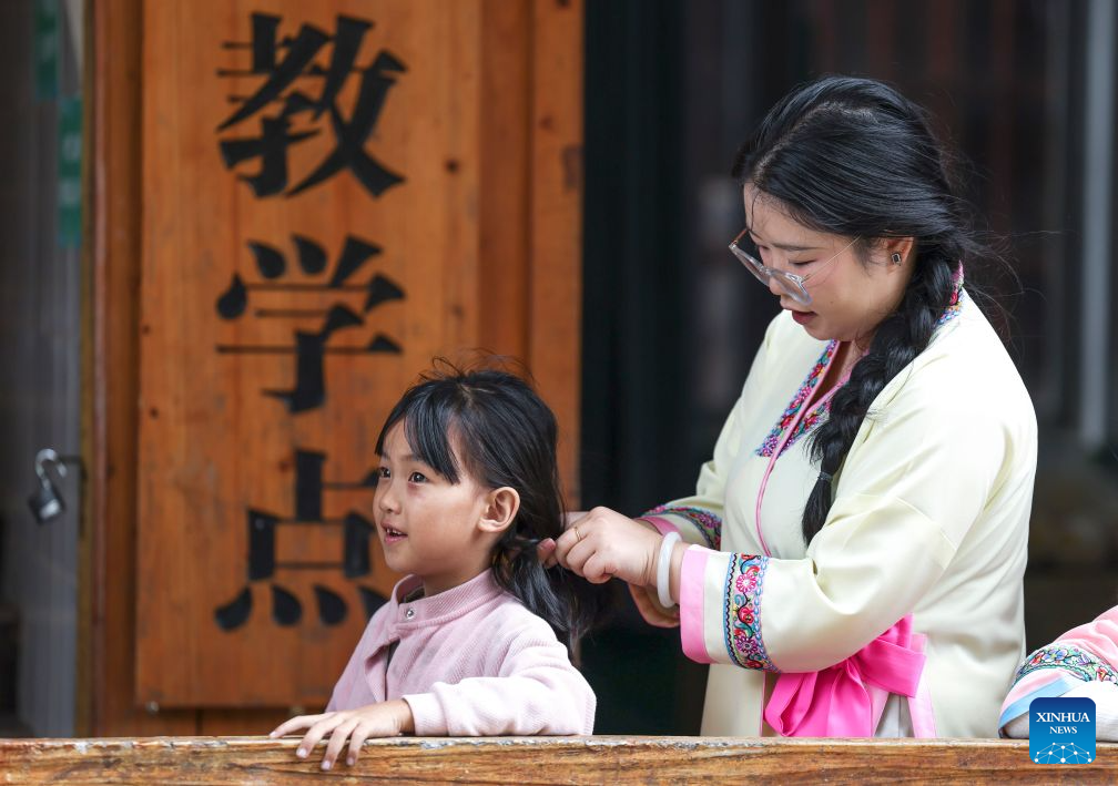 Peng Hanping helps a student tie her hair at the Wuying teaching site in Wuying Village on the border between south China's Guangxi Zhuang Autonomous Region and southwest China's Guizhou Province, Sept. 3, 2026.(Xinhua/Yang Wenbin)