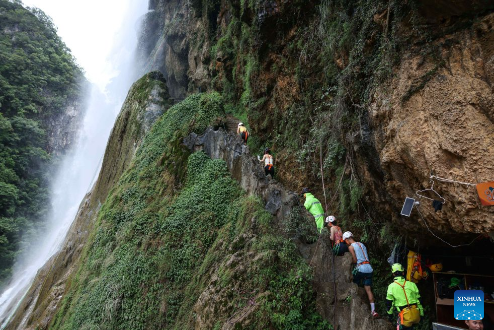 Tourists and staff members head to a waterfall rappelling spot at a scenic area in Huangping County, Qiandongnan Miao and Dong Autonomous Prefecture, southwest China's Guizhou Province, July 29, 2026. The waterfall rappelling here has attracted tourists for cool relief and exhilarating experience. (Xinhua/Yang Wenbin)