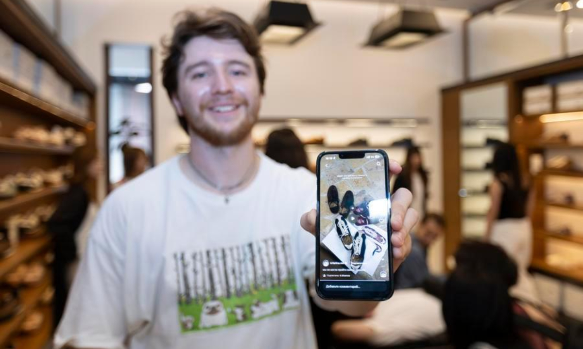 Maksim Ermolaev, a tourist from Russia, shows shoes from a Chinese brand that he has seen on social media at a shop in Shanghai, east China, July 22, 2026. (Xinhua/Wang Xiang)