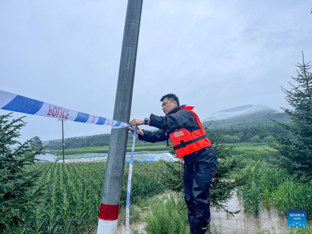 A police officer sets up a security cordon at a dangerous section of a road in Jiguan Township of Wangqing County, northeast China's Jilin Province, July 29, 2026. Heavy rainfall has caused flood in Wangqing and trapped residents. Local authorities have carried out emergency rescue and response. (Wangqing Public Security Bureau/Handout via Xinhua)