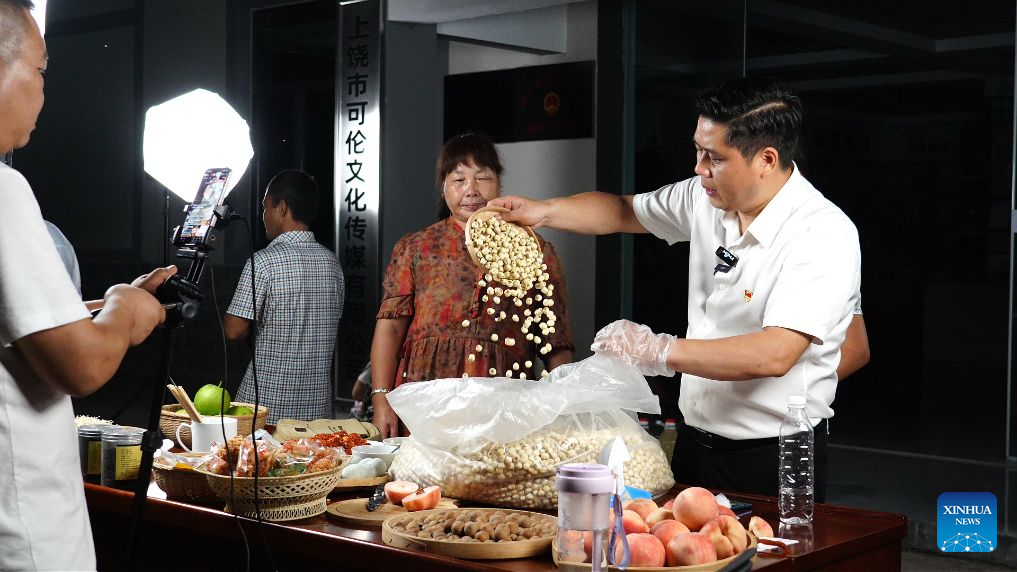 Chen Jianguo (1st R), Party secretary of Beishan Village, promotes agricultural products at a livestream session in Beishan Village of Guangxin District in Shangrao City, east China's Jiangxi Province, July 23, 2026.
Chen Jianguo, Party secretary of Beishan Village, opened social media accounts to post farm produce promotion clips and leveraged livestreaming to sell local agricultural products. Villagers pack their produce up to his livestream sessions one after another, creating a bustling scene similar to open-air markets.
As e-commerce is increasingly employed to boost farmers' incomes, Party members and village officials are mobilized to participate actively in livestreaming sales, leading the way in navigating this new path to prosperity. (Xinhua)