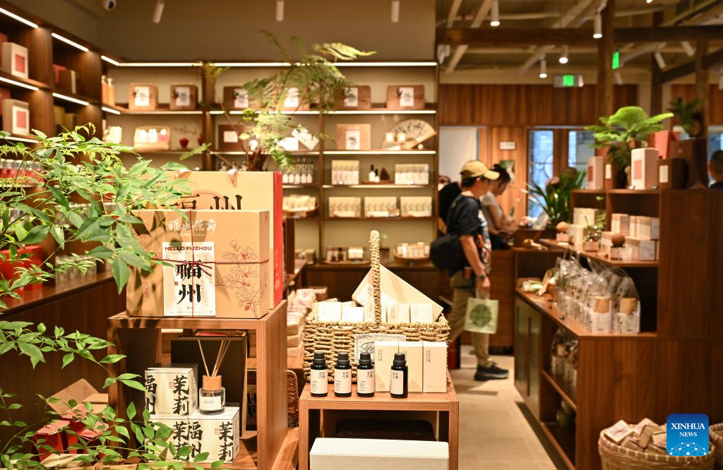 Tourists shop at a jasmine-themed gift store at the Shangxiahang traditional block in Fuzhou, southeast China's Fujian Province, on July 22, 2026. Fuzhou's traditional jasmine tea scenting craftsmanship, a national intangible cultural heritage, is driving the city's cultural tourism development. Leveraging its century-old jasmine tea industrial heritage, the city has restored historic tea plantations and scenting workshops while developing tea-themed industrial, educational and cultural attractions. In recent years, the renowned jasmine tea heritage has been transformed into a vibrant driver of the city's cultural tourism growth. (Xinhua/Han Xu)