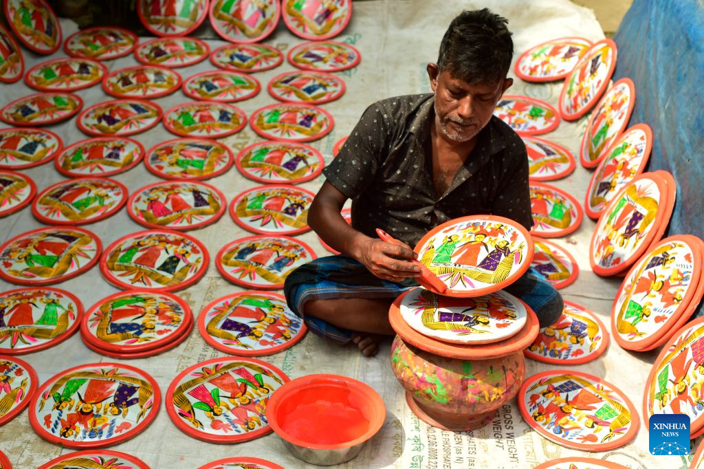An artisan makes a traditional Lakshmi Sara in Munshiganj district, Bangladesh, Oct. 11, 2026. Lakshmi Sara is a round earthenware plate typically decorated with images of the Hindu goddess Lakshmi and other motifs and used in religious rituals. (Photo by Habibur Rahman/Xinhua)