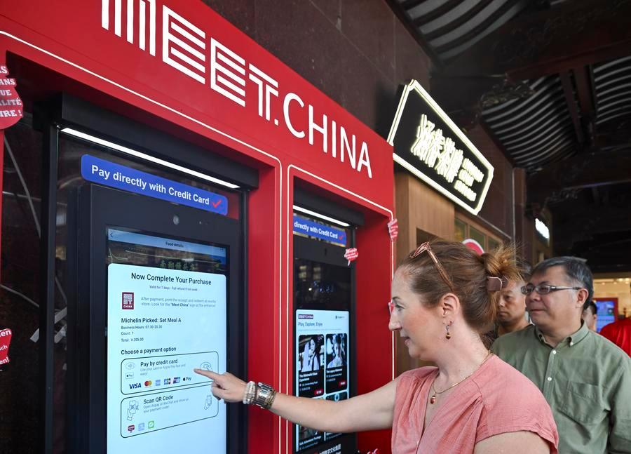 A foreign guest tries to use the Meet China Inbound Tourism Digital Consumption Screen in Yuyuan Garden, Shanghai, east China, Sept. 27, 2025. (Xinhua/Chen Haoming)
