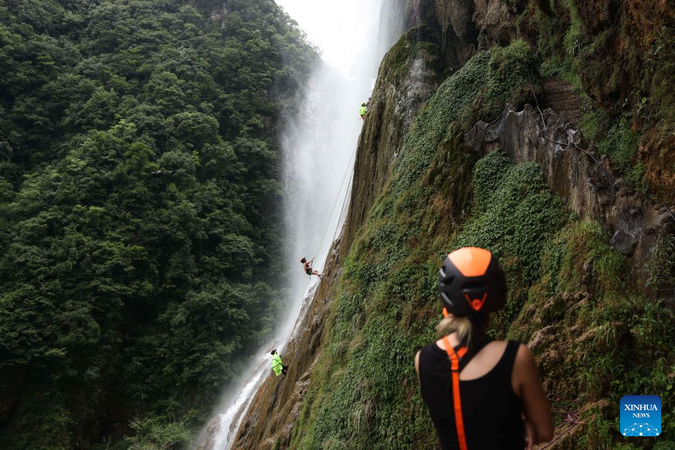 Tourists experience waterfall rappelling under the guidance of staff members at a scenic area in Huangping County, Qiandongnan Miao and Dong Autonomous Prefecture, southwest China's Guizhou Province, July 29, 2026. The waterfall rappelling here has attracted tourists for cool relief and exhilarating experience. (Xinhua/Yang Wenbin)