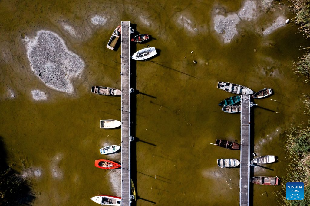An aerial drone photo taken on Aug. 26, 2026 shows a dock of the drought-stricken Lake Velence near Gardony, Hungary. Prolonged drought has pushed Lake Velence, one of Hungary's major lakes, to its lowest level on record. By Aug. 26, the water level had fallen to 16 centimeters, exposing the lakebed along several shallow stretches. (Photo by David Balogh/Xinhua)