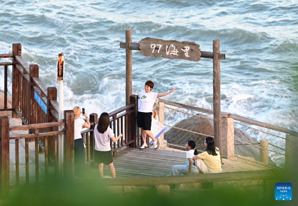 Tourists take photos at a scenic spot in Dazuo Village of Hui'an County, southeast China's Fujian Province, Aug. 17, 2026. Dazuo Village is surrounded by the sea on three sides. In recent years, the village has focused on cultivating the traditional customs, launching experiential activities such as net weaving and travel photography to attract tourists. (Xinhua/Lin Shanchuan)
