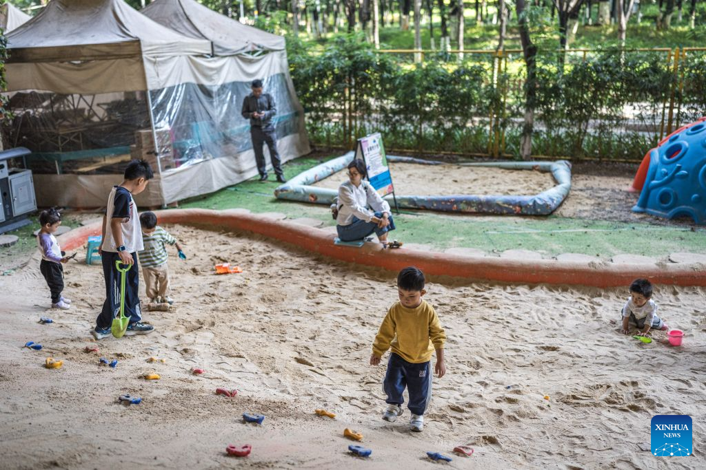 Children play at a playground beneath a flyover in Kunming, southwest China's Yunnan Province, Aug. 11, 2026. In recent years, Kunming has transformed some vacant areas beneath urban bridges and flyovers into public spaces for greenery, leisure, recreation and physical exercises, making the city more livable for residents. (Xinhua/Wang Guansen)