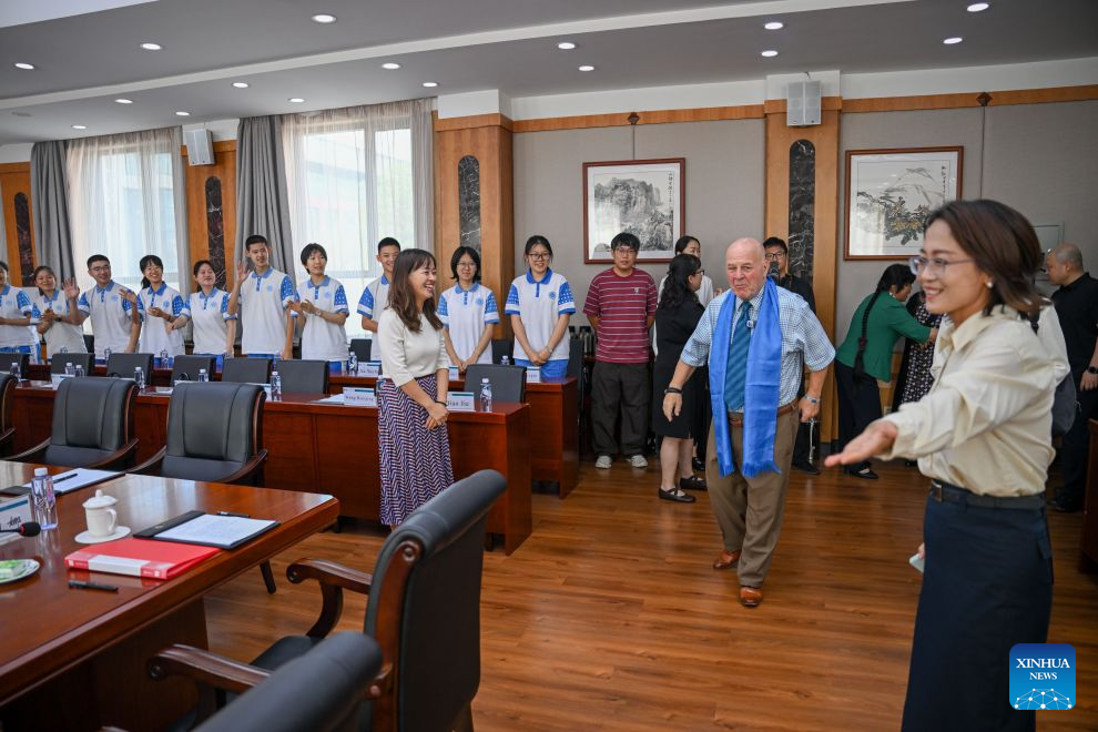 Ronald Sakolsky (C, front) attends a China-U.S. teacher education exchange symposium at a high school in Hohhot, north China's Inner Mongolia Autonomous Region, Aug. 26, 2026.
Ronald Sakolsky, accompanied by Yin Yuzhen, a national model worker, visited Hohhot in Inner Mongolia on Wednesday.
Yin has spent four decades planting trees across northern China's Maowusu Sandy Land, the country's fourth-largest sandy area. Her life-changing cross-border friendship dates back to 1999. That year, Sakolsky watched a TV report covering Yin's arduous sand-control work while teaching in China. Deeply moved, he raised 5,000 U.S. dollars to fund her afforestation work.
The donation enabled Yin to purchase and plant more than 50,000 saplings. Those saplings have since grown into a sprawling forest, turning barren dunes into thriving green space. Earlier this year, Yin reconnected online with her long-lost American friend, who traveled to China on Sunday to revisit the forest he helped create and meet Yin in person. (Xinhua/Lian Zhen)