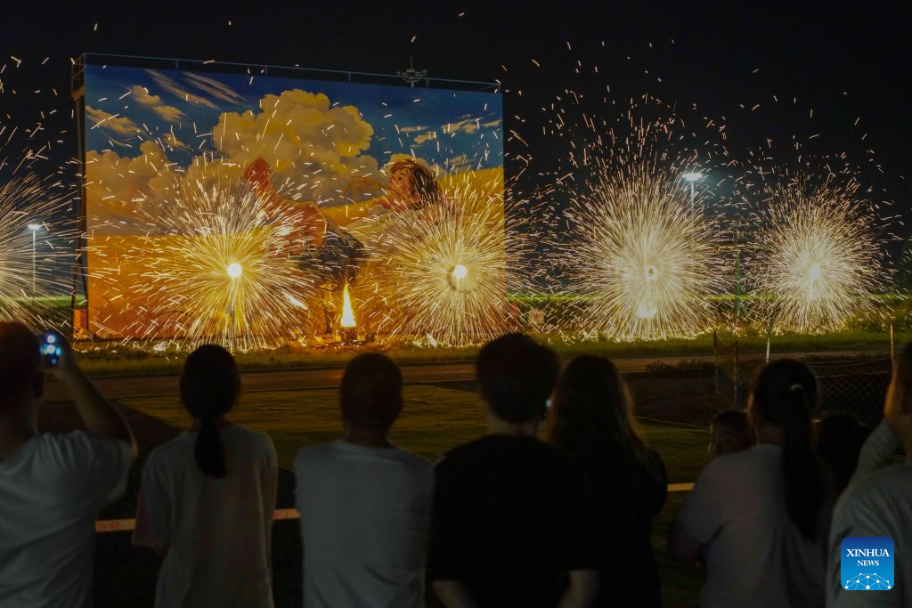 Tourists watch a molten iron fireworks show at a paddy-field scenic area in Shanligezhuang Village of Zunhua, north China's Hebei Province, Aug. 10, 2026. (Photo by Liu Mancang/Xinhua)