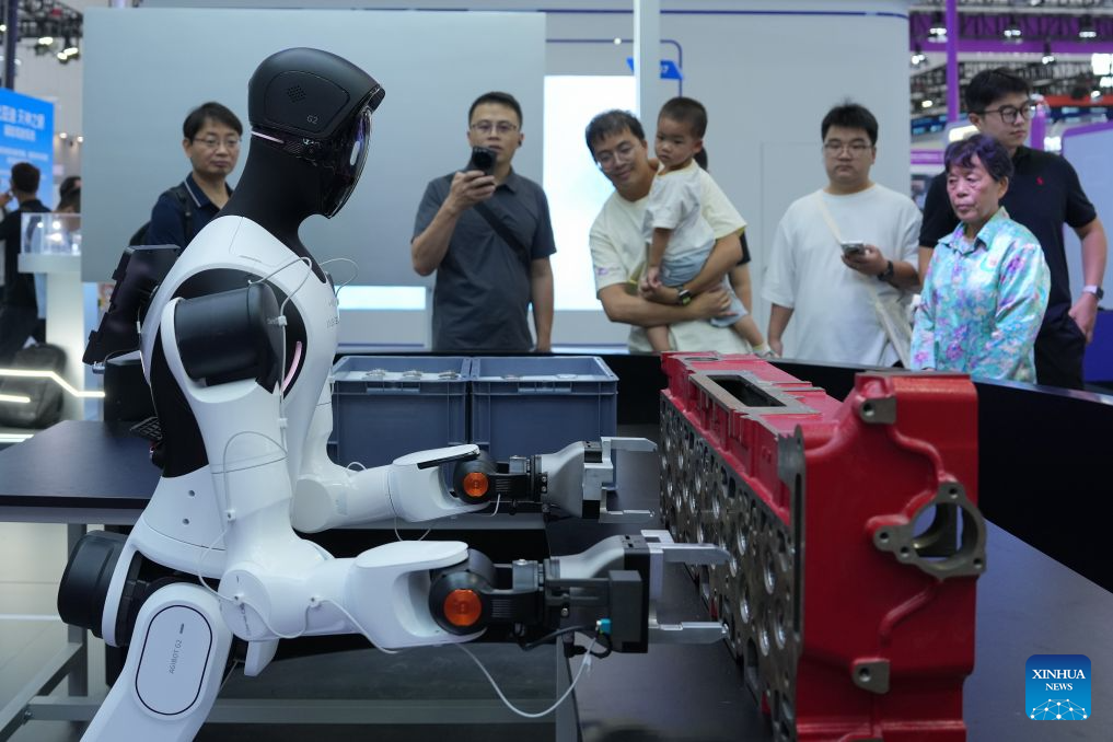 People learn about a humanoid robot applied to workshop production and assembly during the 2026 Apsara Conference in Hangzhou, east China's Zhejiang Province, Sept. 22, 2026. The 2026 Apsara Conference opened here on Tuesday, and will last for three days. The conference has three main forums and more than 120 sub-forums. (Xinhua/Huang Zongzhi)