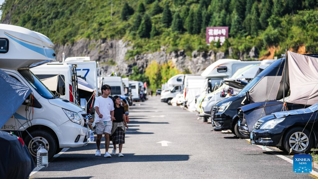 Campers take a walk at a RV (recreational vehicles) camping base in Bijie City, southwest China's Guizhou Province, Aug. 11, 2026. In recent years, Bijie City has leveraged its scenic natural environment and pleasant mountain climate to promote the development of RV camping bases and boost summer tourism, drawing RV travelers from across China. (Xinhua/Tao Liang)