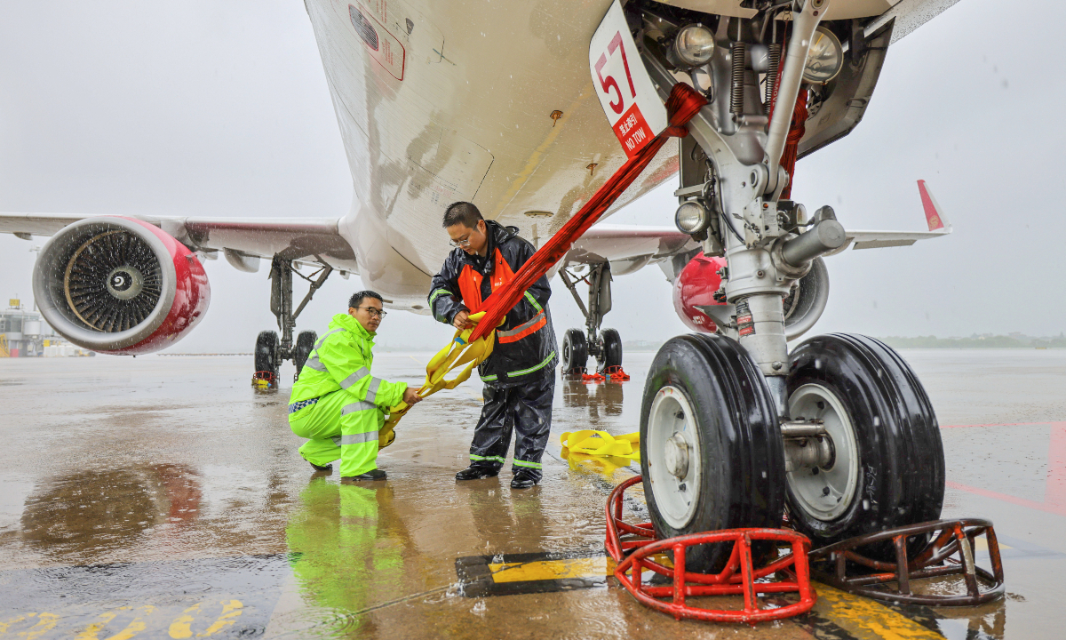 Staff members tie an airplane to ground at Hangzhou Xiaoshan International Airport in East China's Zhejiang Province to prepare 
for Typhoon Dolphin on August 9, 2026. Photo: VCG