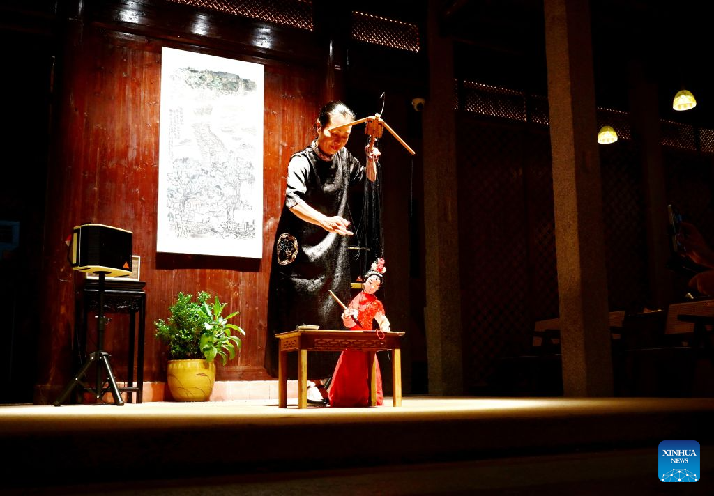 An artist performs writing Chinese calligraphy with a marionette at a mansion on the Qiaonan ancient street in Quanzhou City, southeast China's Fujian Province, Aug. 18, 2026. Qiaonan ancient street in Quanzhou is a historical and cultural block which still preserves traditional Minnan buildings and overseas-Chinese mansions. Minnan literally means southern Fujian Province. In recent years, local government has promoted the protection and utility of this block by rolling out innovative management mode. (Xinhua/Lin Shanchuan)
