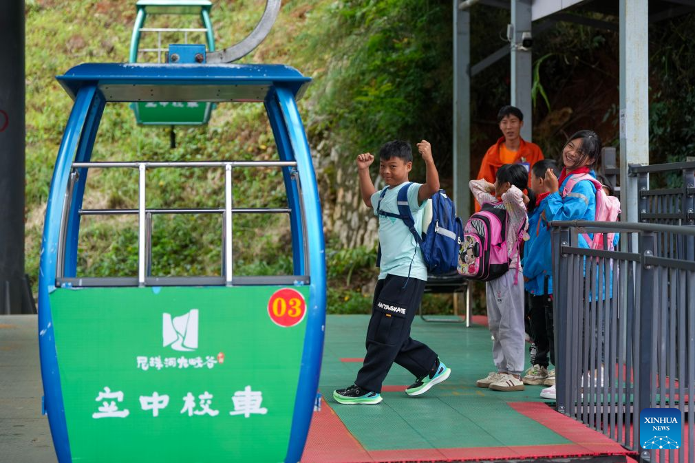 Students wait for cable cars in Puli Township, Xuanwei City, southwest China's Yunnan Province, Aug. 30, 2026. Nizhuhe Village is located at the bottom of the Nizhu River Grand Canyon in southwest China's Yunnan Province. What separates Nizhuhe Village and the Guanzhai primary school on the mountain top is a vertical drop of over 500 meters. Students living at the canyon bottom used to take nearly half a day to travel from home to school.
In 2022, significant changes in the means of local commuting took place upon the completion and opening of the Nizhu River Grand Canyon scenic area, which came with a 268-meter-high cliff elevator and a cable car system that were available to local villagers, including students, free of charge.
Today, the combination of sightseeing shuttle vehicles, elevators and cable cars has shortened students' journey to school to about 30 minutes. A dedicated passage has also been set up for them, with police officers and dedicated staff members deployed along the commuting route. (Xinhua/Chen Xinbo)
