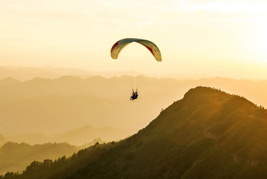An aerial photo taken on July 30, 2026 shows a tourist experiencing paragliding with a pilot at a paragliding base in Jiuzhou Town, Huangping County, southwest China's Guizhou Province. (Xinhua/Yang Wenbin)