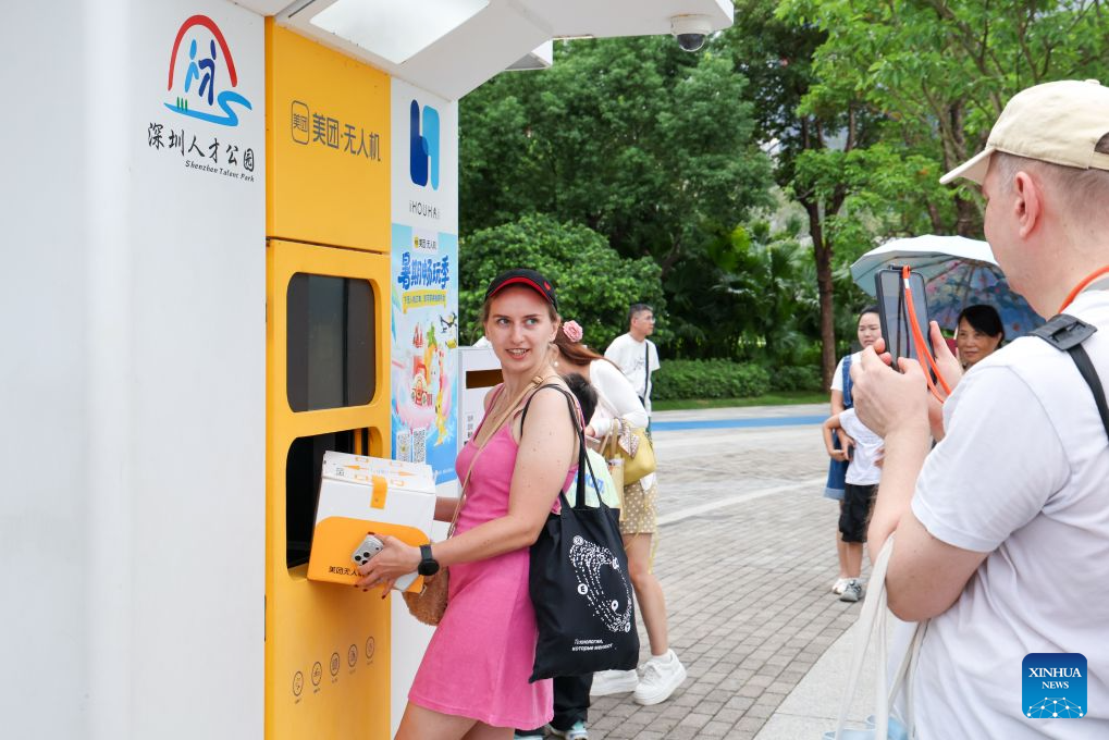 Foreign tourists experience Meituan's unmanned delivery service at a park in Shenzhen, south China's Guangdong Province, Aug. 3, 2026. With the deep application of the achievements of emerging industries, many inbound foreign tourists choose science and technology tour as the theme of their journey in the Chinese cities.
In Shenzhen, foreign tourists are attracted by AI applications and technology scenarios in daily life, such as AI glasses, smart robots and unmanned delivery service. (Xinhua/Liang Xu)