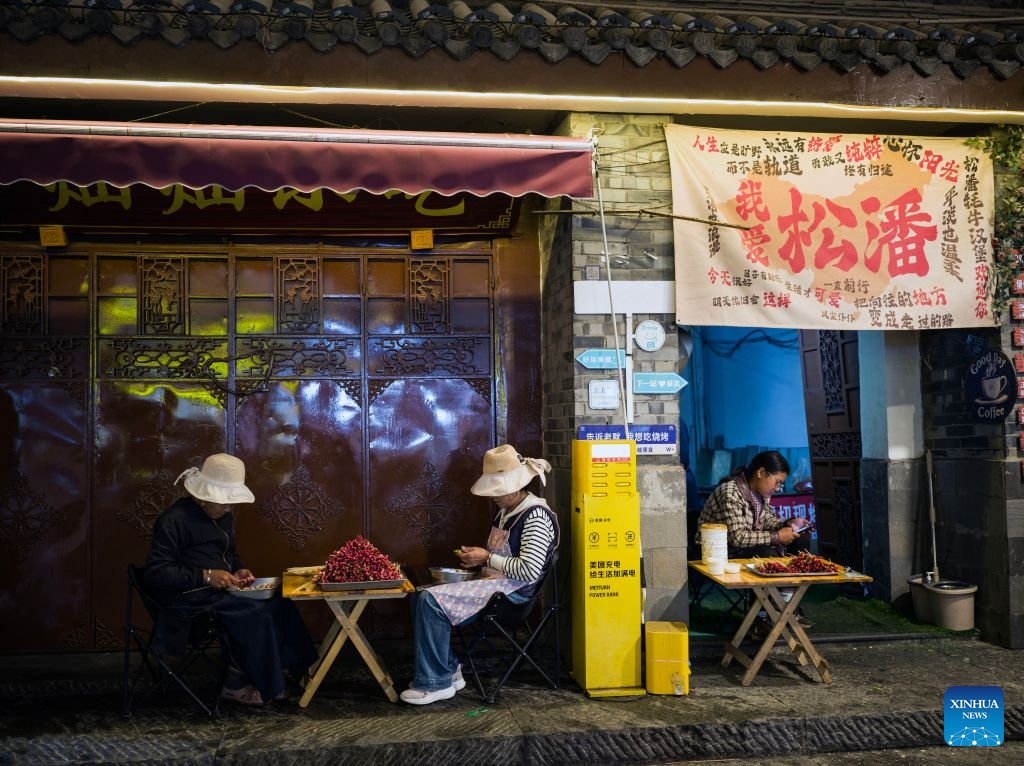 Staff members of a barbecue shop work at Songzhou Ancient City in Songpan County of Aba Tibetan and Qiang Autonomous Prefecture, southwest China's Sichuan Province, Aug. 23, 2026. Songzhou Ancient City in Songpan County is now a major historical and cultural site protected at the national level. (Photo by Lan Hongguang/Xinhua)