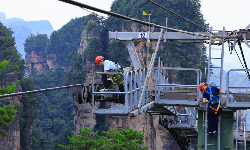 Workers perform safety inspections and maintenance on the cableway equipment in the Zhangjiajie National Forest Park, also known as home to the