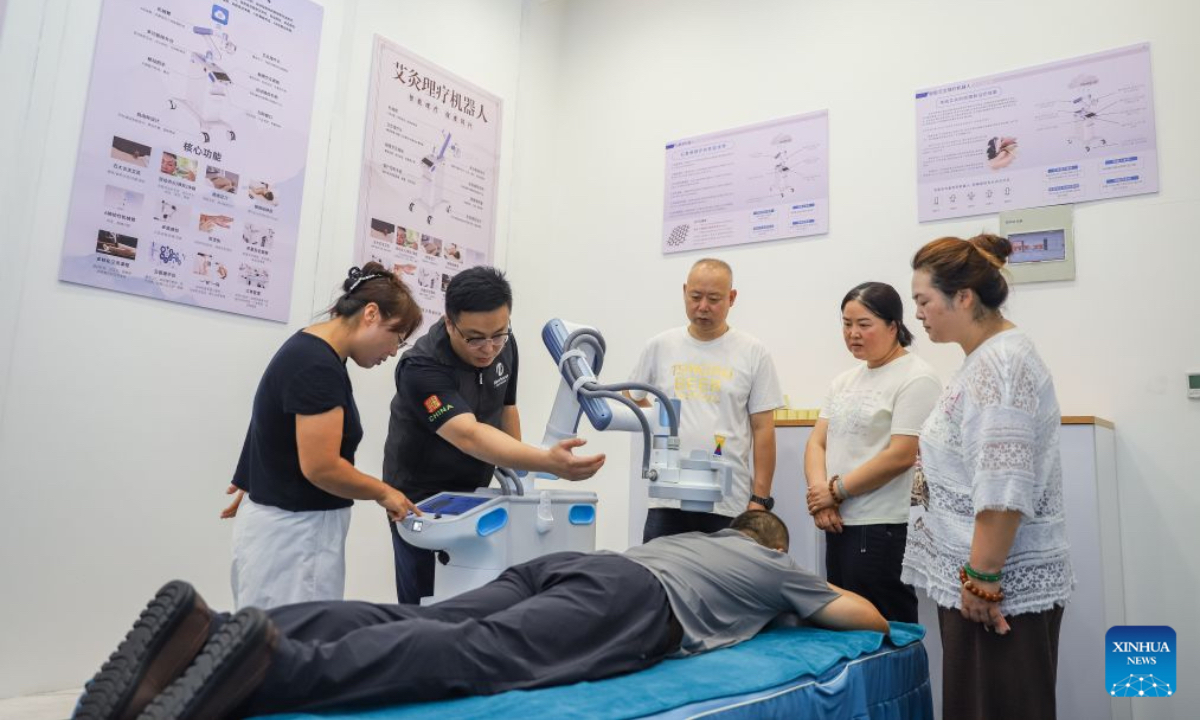 An instructor teaches trainees to operate a therapy robot at a training center of domestic services in Qingdao City, east China's Shandong Province, July 21, 2026. A number of domestic services brands have emerged in Shandong in recent years, offering widely ranging services such as eldercare, maternity care, and in-home caregiving. (Photo by Zhang Ying/Xinhua)