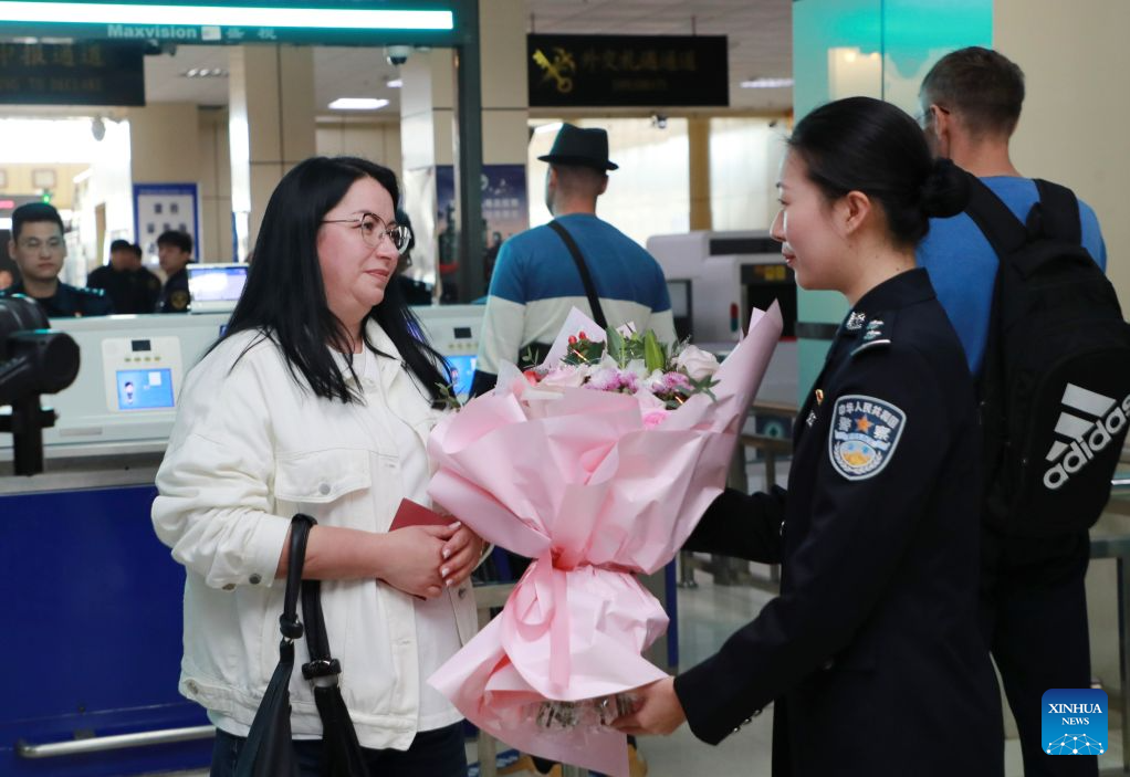 A police officer of the Heihe border inspection station presents flowers to a Russian passenger, who is the one-millionth passenger going through customs in Heihe this year, at a port in Heihe, northeast China's Heilongjiang Province, Sept. 14, 2026. Cross-border personnel exchanges at the Heihe Port are getting more and more active since the implementation of the visa-free policy between China and Russia. The number of inbound and outbound passenger trips through the port since the beginning of 2026 has hit a record high of 1 million until Monday, an increase of 56.18 percent year on year. (Photo by Liu Song/Xinhua)