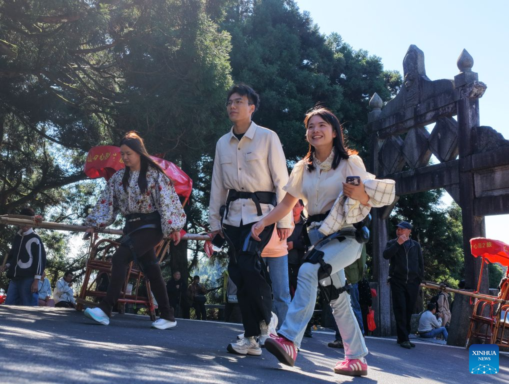 Tourists wearing exoskeleton robots hike at the Hengshan Mountain scenic area in Hengyang City, central China's Hunan Province, Oct. 6, 2026. Advanced technologies such as exoskeleton devices, AI-powered glasses and robots have enabled diverse and dazzling experiences at tourist destinations across China during the National Day holiday. (Photo by Cao Zhengping/Xinhua)