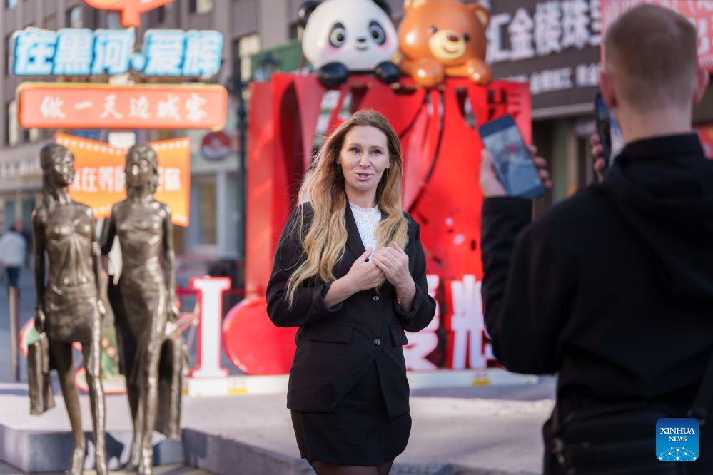 A Russian tourist takes photos on a pedestrian street in Heihe, northeast China's Heilongjiang Province, Sept. 15, 2026. Cross-border tourism and people-to-people exchanges between China and Russia have become more active since the introduction of optimized visa-free policies in 2025. (Photo by Zhao Donglai/Xinhua)