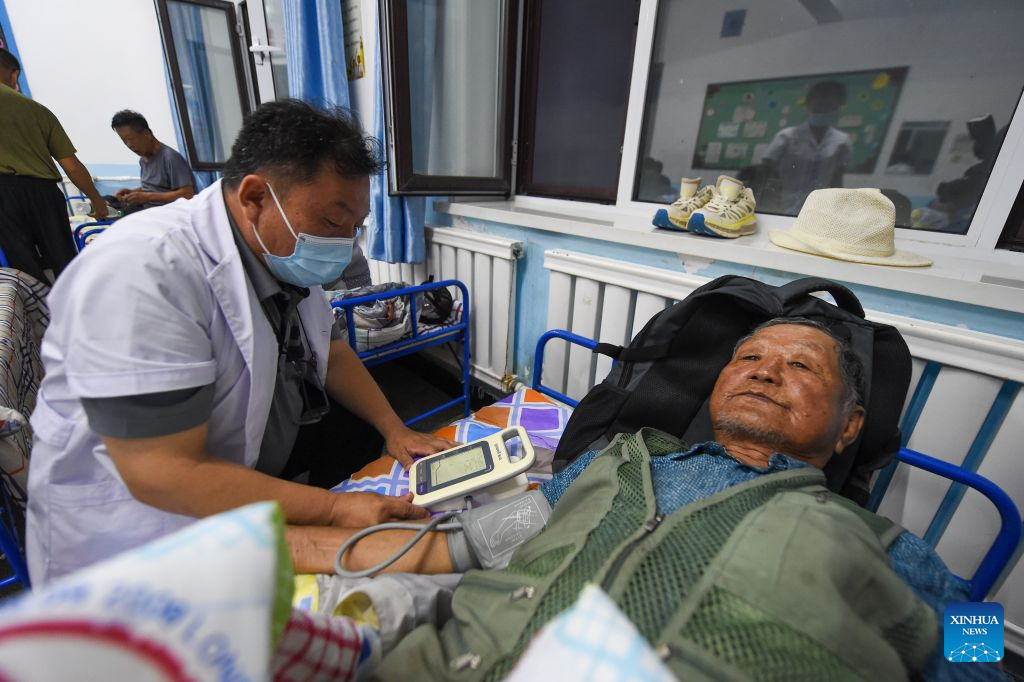 A doctor conducts health check for a resident at a temporary shelter in Xinxing Village, Dongguang Town, Wangqing County, northeast China's Jilin Province, July 29, 2026. Heavy rainfall has caused flood in Wangqing and trapped residents. Local authorities have carried out emergency rescue and response. (Xinhua/Zhang Nan)