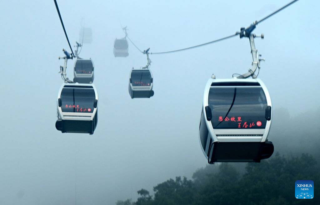 Tourists take cable cars at the Wangwu Mountain scenic spot in Jiyuan, central China's Henan Province, Aug. 22, 2026. The Wangwu Mountain scenic spot witnesses a tourism boom during the summer vacation. (Xinhua/Zhu Xiang)