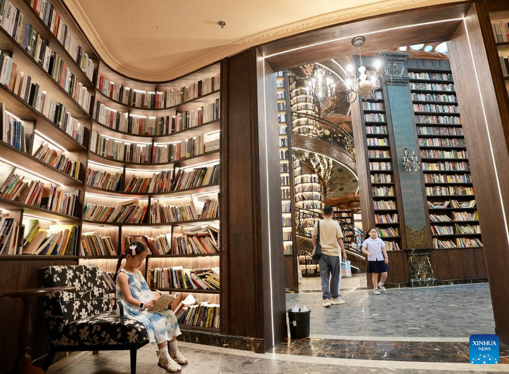 People visit a sinkhole-turned library in Wuyuan County, east China's Jiangxi Province on Aug. 26, 2026. A special sinkhole-turned library opened to the public recently in Wuyuan County of east China's Jiangxi Province. It incorporates a natural sinkhole and surrounding rock walls into its architecture. The library features a carved spiral staircase and warm lighting, offering visitors a distinctive reading experience. (Xinhua/Hu Chenhuan)