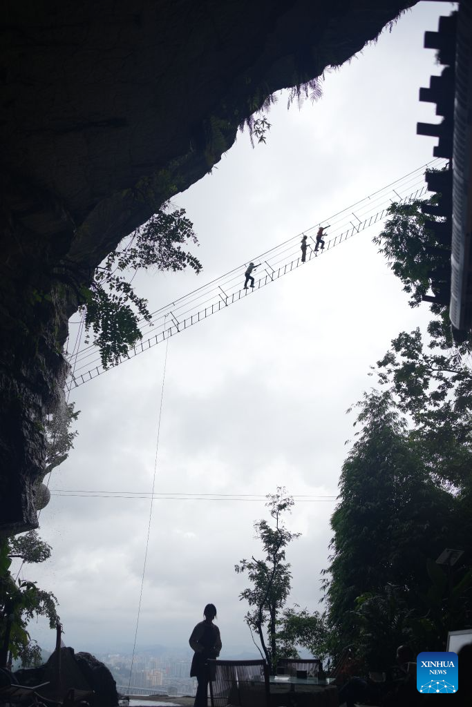 Tourists enjoy via ferrata climb at a karst cave in Zunyi City, southwest China's Guizhou Province, Aug. 7, 2026. Best known for its karst landscape, Guizhou has made the best of karst caves to develop distinctive sites for cooling retreats. Featuring natural geological wonders, cooling enjoyment and water amusements, this emerging tourist experience has become a hit among locals and visitors alike. (Photo by Zhang Zhengju/Xinhua)