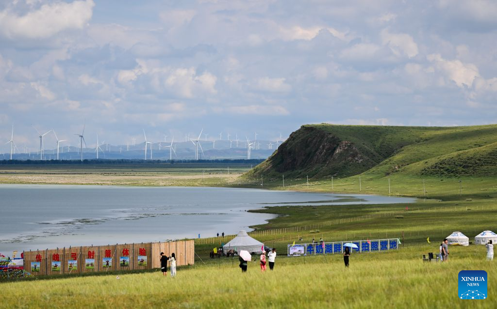 Tourists play by Baiyin Chagan Lake, or Milky Lake, in Xilin Gol League, north China's Inner Mongolia Autonomous Region, Aug. 4, 2026. The lake is dubbed Milky Lake as tiny mineral particles float in the water, turning it creamy-white like milk. (Xinhua/Lian Zhen)
