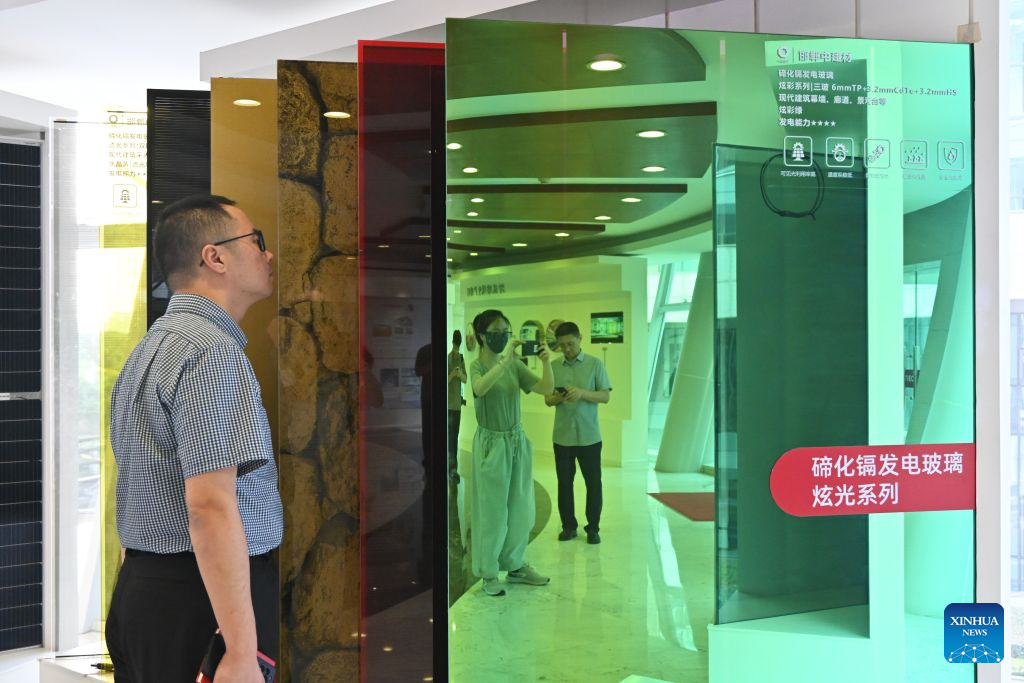 A visitor views CdTe photovoltaic glass products at the Bengbu Glass Industry Design and Research Institute of the China National Building Material Group Co., Ltd. in Bengbu, east China's Anhui Province, Aug. 8, 2026. Rooted in its glass industry, Bengbu has in recent years made breakthroughs in core technologies, successfully developed new glass products such as ultra-thin display glass and hollow glass microspheres, and established a complete industrial chain from quartz sand to end-user applications. (Photo by Lin Qiujin/Xinhua)