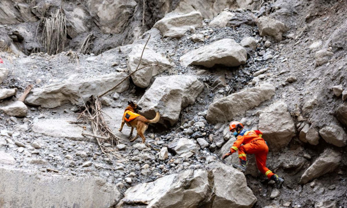 A rescuer and his sniffer dog search for the missing at the mudslide-hit area in Gyirong County, southwest China's Xizang Autonomous Region, Aug. 30, 2026.  (Xinhua/Jiang Fan)