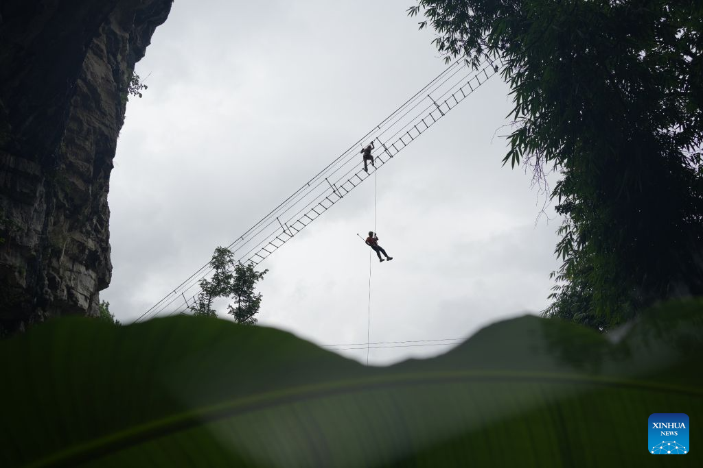 Tourists enjoy via ferrata climb at a karst cave in Zunyi City, southwest China's Guizhou Province, Aug. 7, 2026. Best known for its karst landscape, Guizhou has made the best of karst caves to develop distinctive sites for cooling retreats. Featuring natural geological wonders, cooling enjoyment and water amusements, this emerging tourist experience has become a hit among locals and visitors alike. (Photo by Zhang Zhengju/Xinhua)